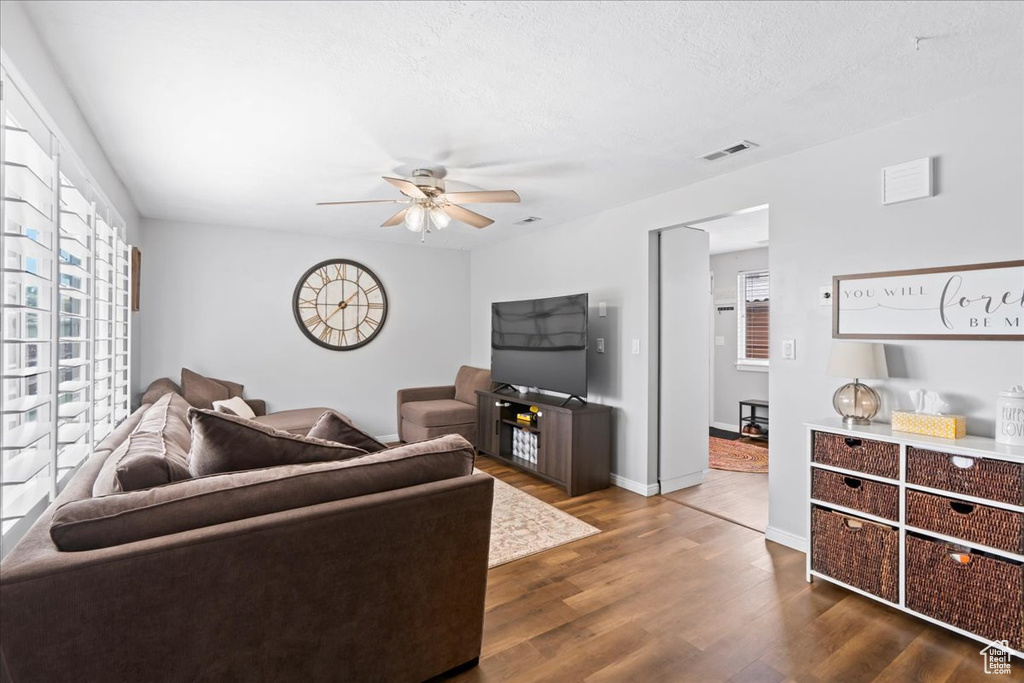 Living room featuring visible vents, dark wood-style flooring, baseboards, ceiling fan, and a textured ceiling