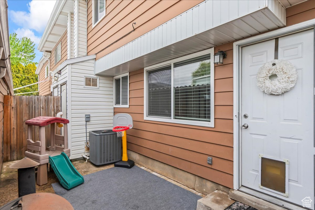 Doorway to property featuring central air condition unit and fence