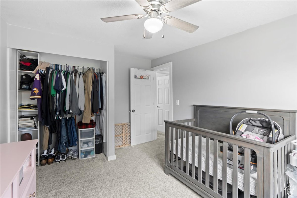 Carpeted bedroom with ceiling fan and a closet