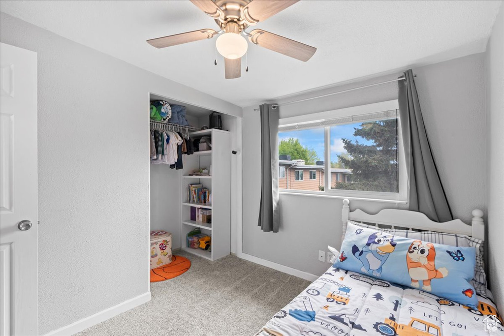 Carpeted bedroom with a ceiling fan, baseboards, and a closet