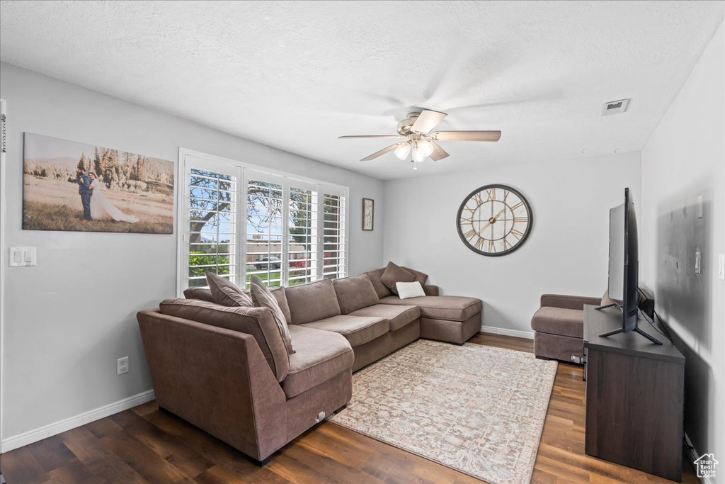 Living room with baseboards, ceiling fan, dark wood finished floors, and visible vents