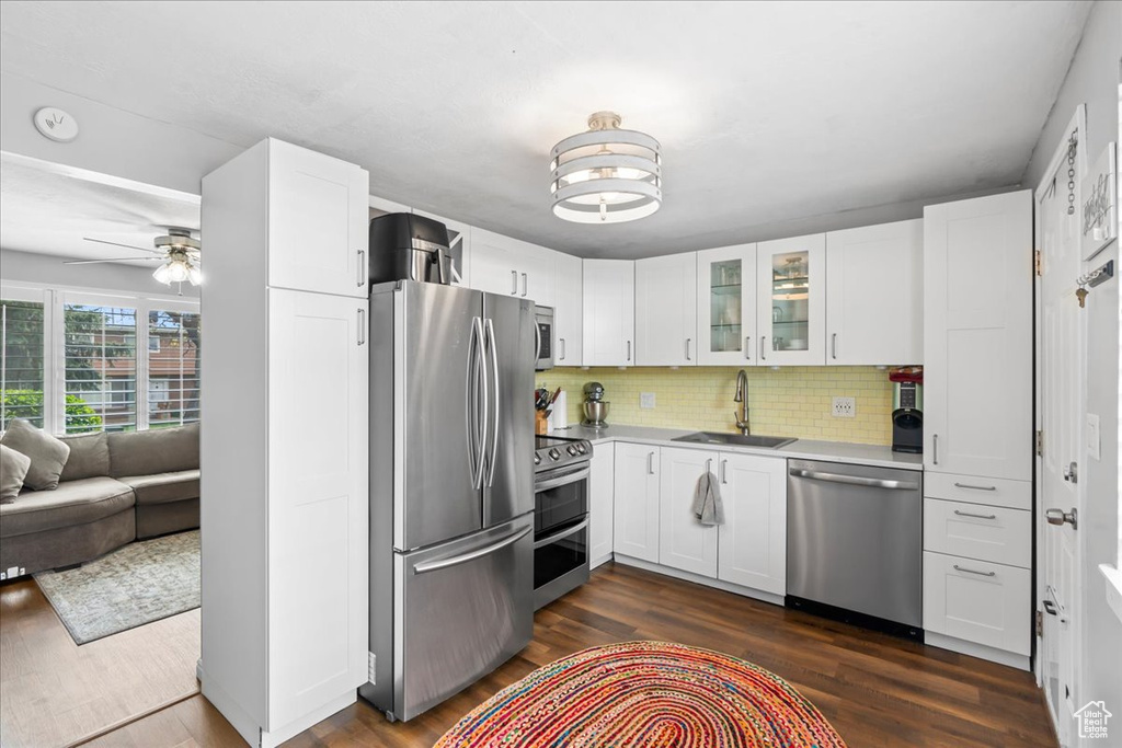 Kitchen with glass insert cabinets, dark wood-style floors, light countertops, a sink, and stainless steel appliances