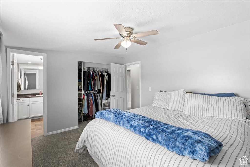Carpeted bedroom with a closet, baseboards, ensuite bathroom, and ceiling fan
