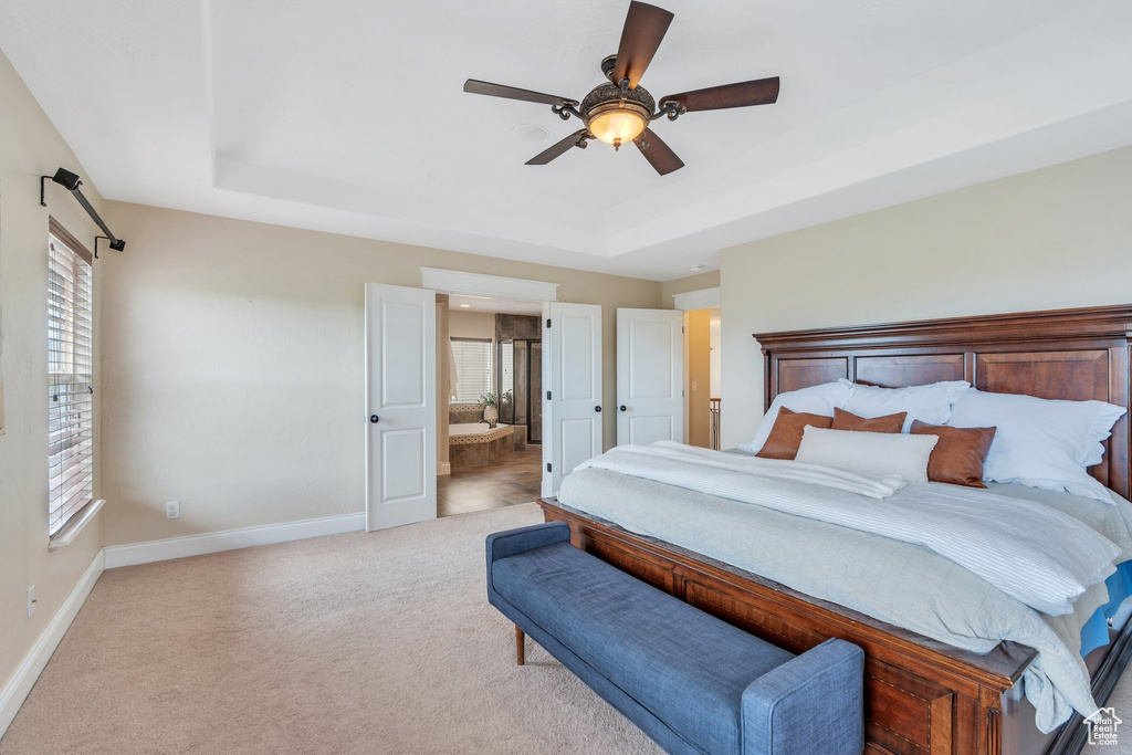 Bedroom featuring a tray ceiling, multiple windows, and baseboards