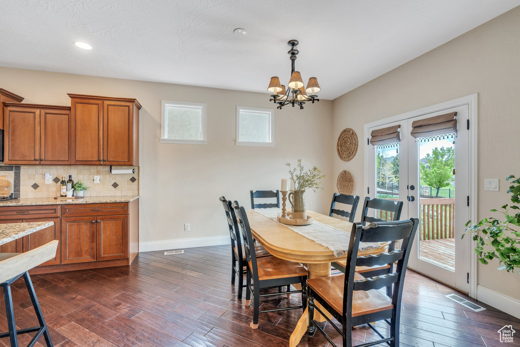 Dining room featuring an inviting chandelier, baseboards, a wealth of natural light, and dark wood-style floors