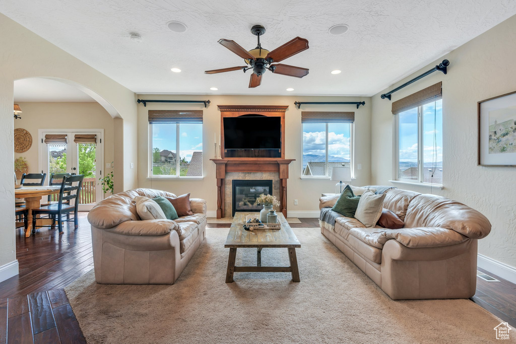 Living area featuring baseboards, arched walkways, ceiling fan, and wood finished floors