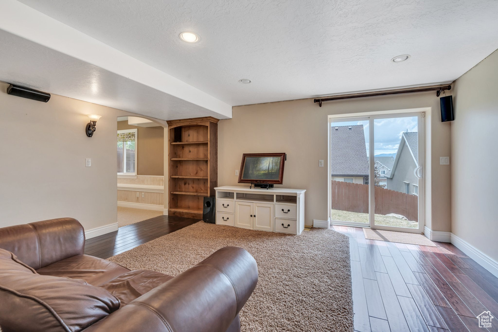 Living area featuring arched walkways, baseboards, dark wood finished floors, and recessed lighting