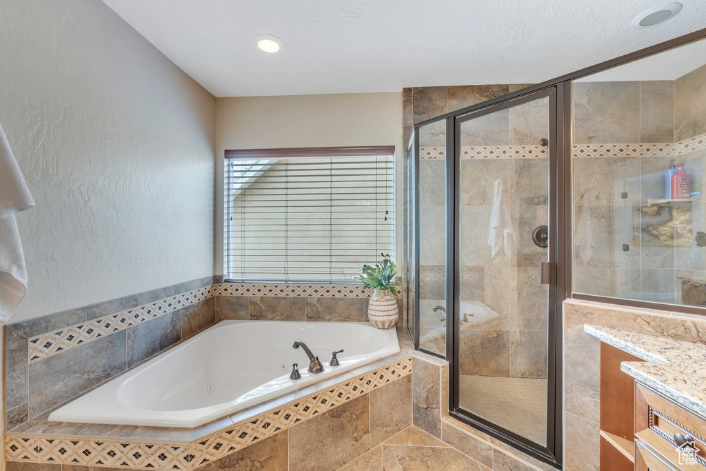 Full bath featuring a stall shower, a garden tub, and vanity