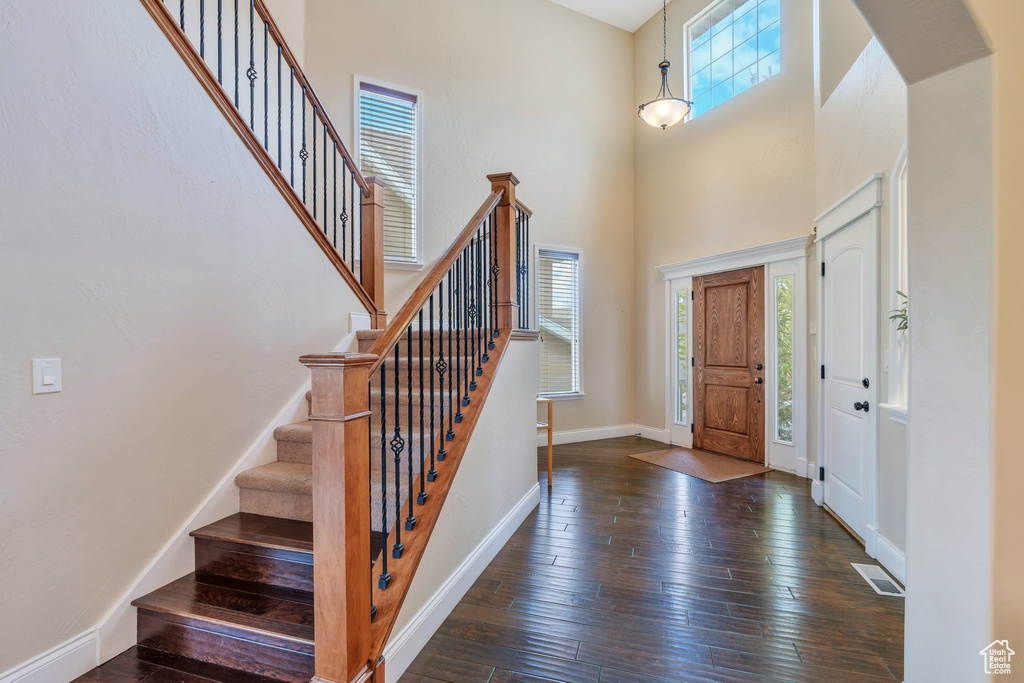 Foyer with visible vents, a towering ceiling, hardwood / wood-style flooring, stairway, and baseboards