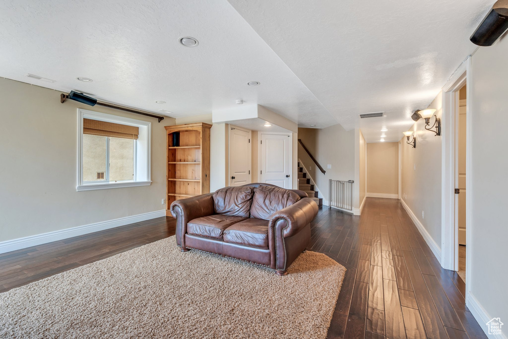 Living room featuring baseboards, visible vents, dark wood-style floors, and stairs