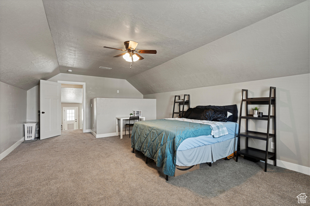 Bedroom with baseboards, ceiling fan, a textured ceiling, carpet flooring, and vaulted ceiling