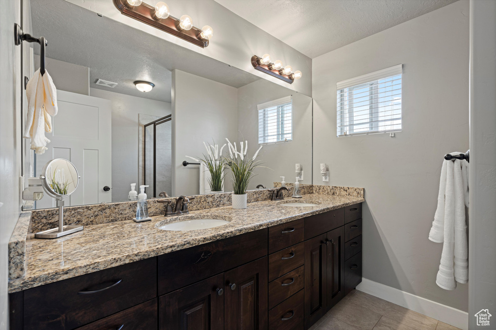 Full bath featuring a sink, baseboards, double vanity, and visible vents