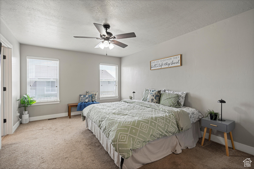 Carpeted bedroom with a textured ceiling, baseboards, and ceiling fan