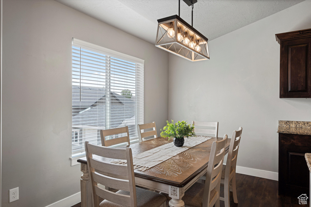 Dining area with baseboards, dark wood-style floors, and an inviting chandelier