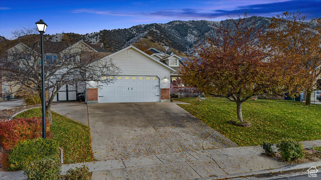 Traditional-style home with brick siding, a garage, a front yard, a mountain view, and concrete driveway