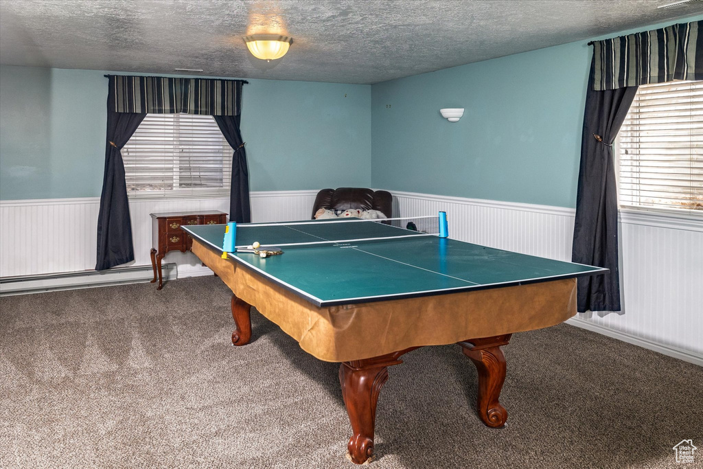 Playroom featuring carpet flooring, a baseboard heating unit, a textured ceiling, and a wainscoted wall