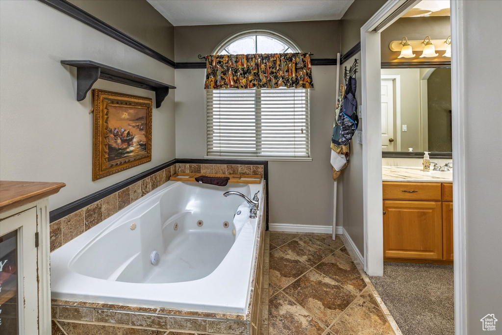 Full bathroom featuring vanity, baseboards, and a jetted tub