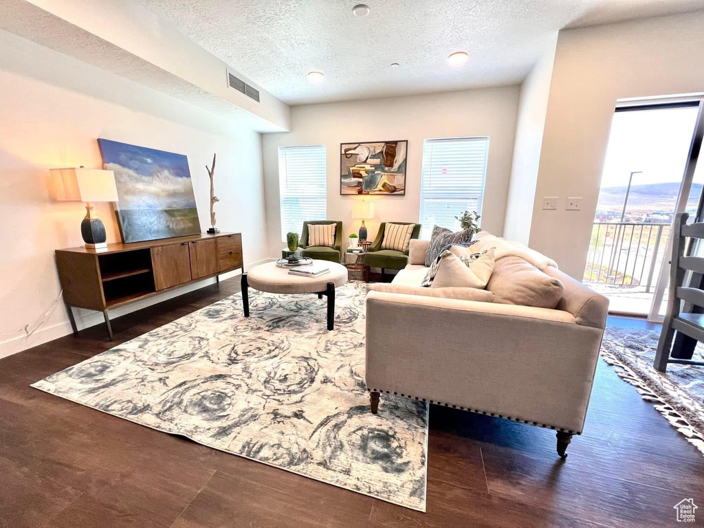 Living area featuring a textured ceiling, visible vents, plenty of natural light, and wood finished floors