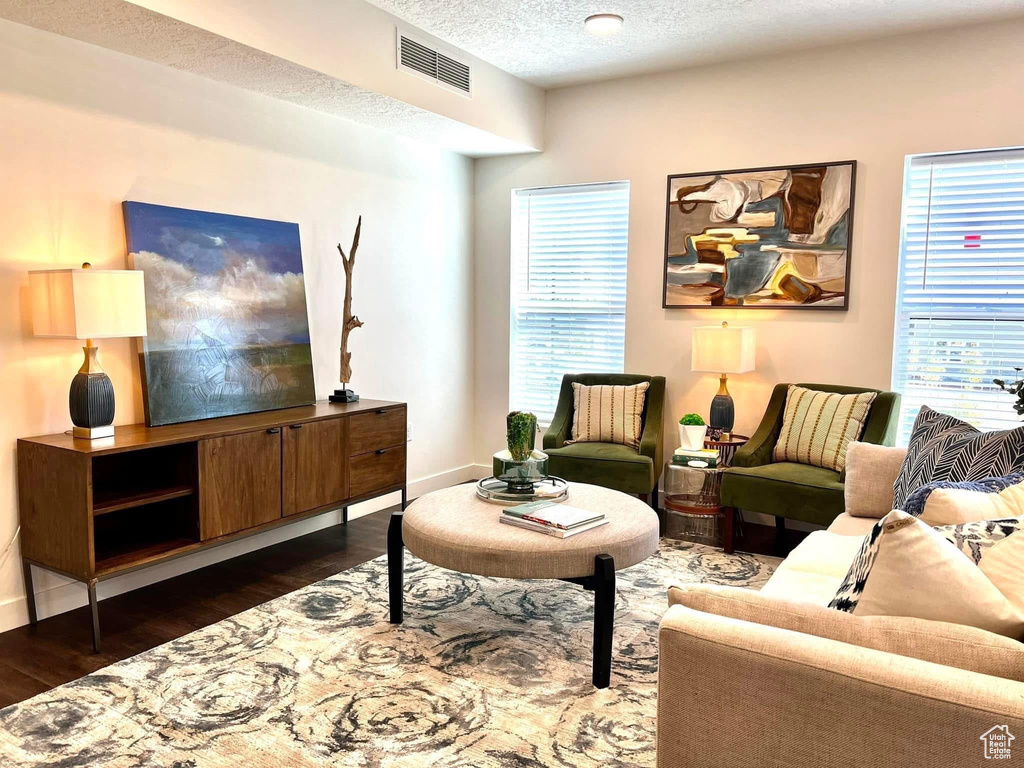 Living area featuring visible vents, a textured ceiling, dark wood finished floors, and baseboards