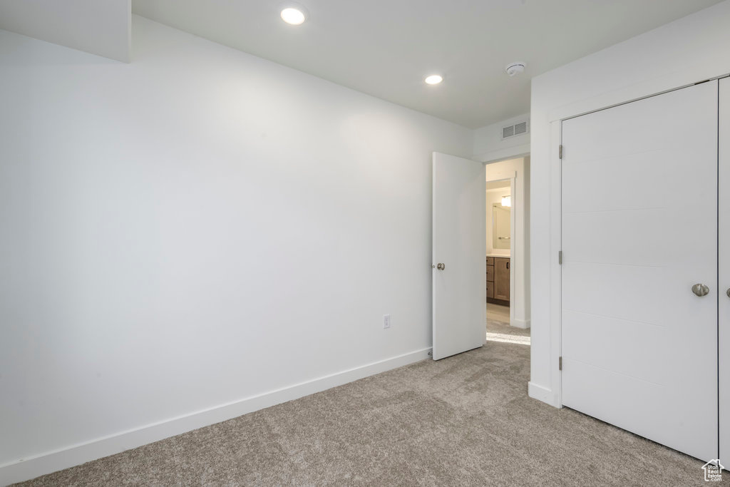 Unfurnished bedroom with light colored carpet, recessed lighting, baseboards, visible vents, and a closet