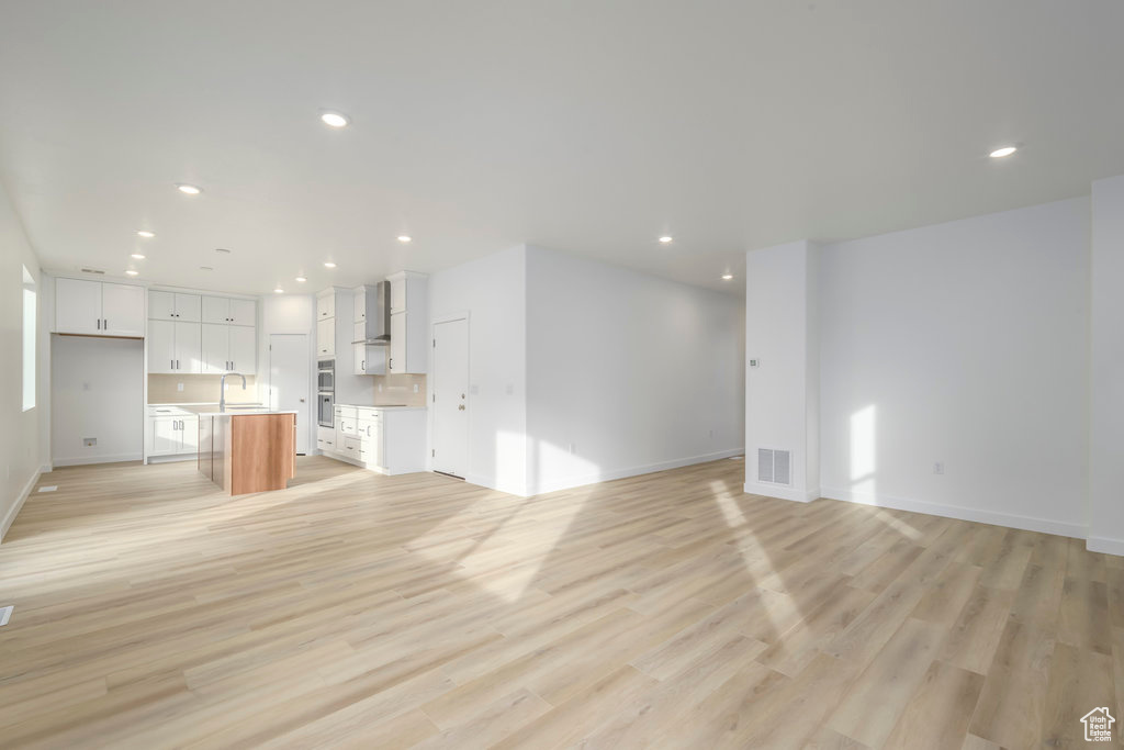 Unfurnished living room with recessed lighting, baseboards, visible vents, and light wood-style floors