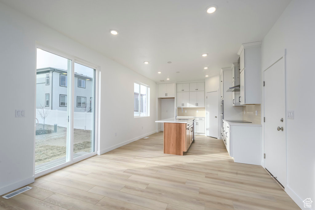 Kitchen featuring visible vents, a center island with sink, recessed lighting, light countertops, and light wood-style flooring