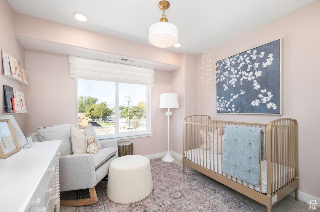 Bedroom with baseboards, a nursery area, and visible vents