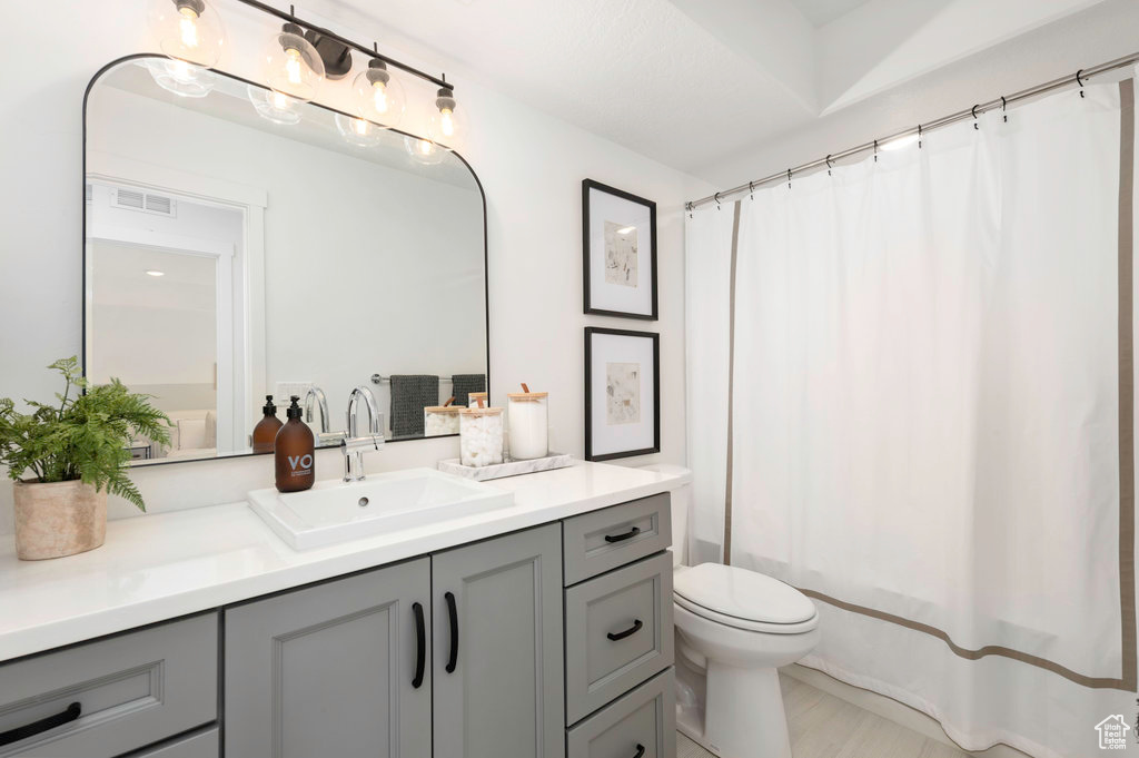 Bathroom featuring toilet, visible vents, shower / tub combo with curtain, and vanity
