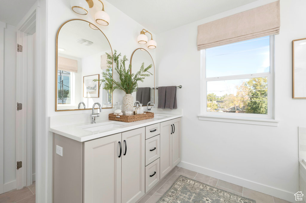 Bathroom featuring double vanity, a wealth of natural light, and a sink