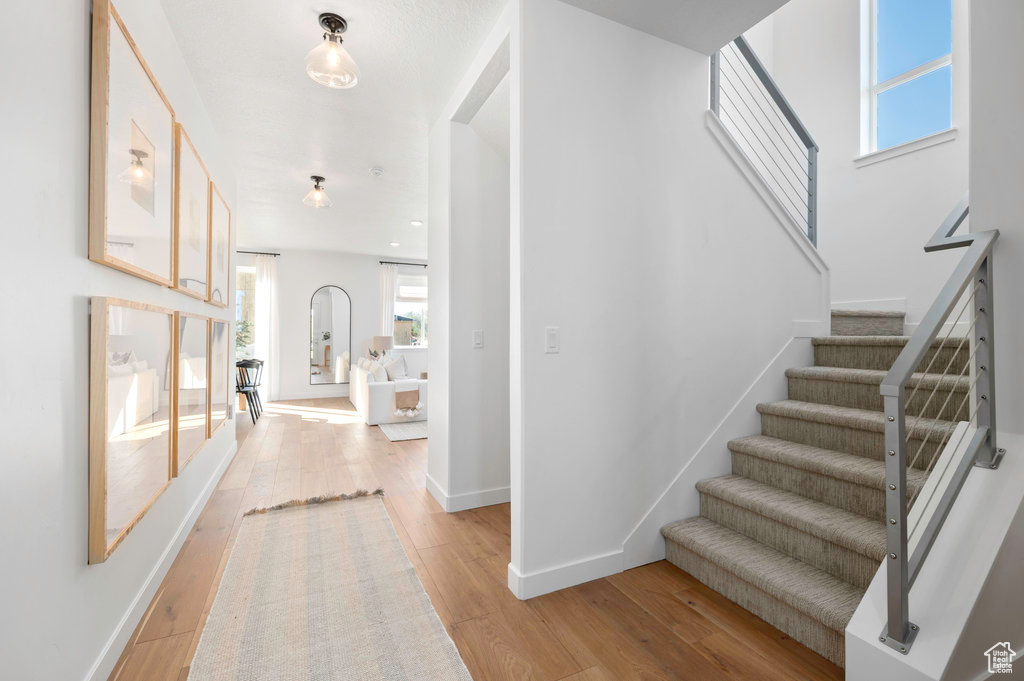 Entrance foyer with stairway, baseboards, light wood-type flooring, and arched walkways
