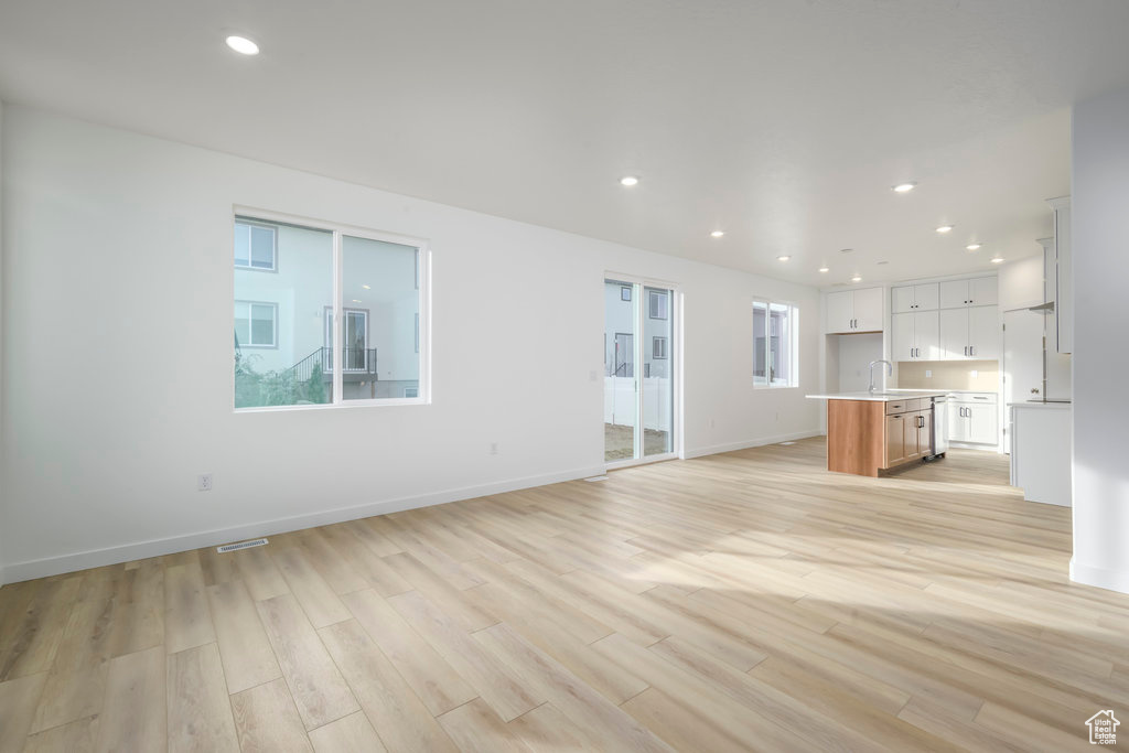 Unfurnished living room with baseboards, recessed lighting, and light wood-style flooring