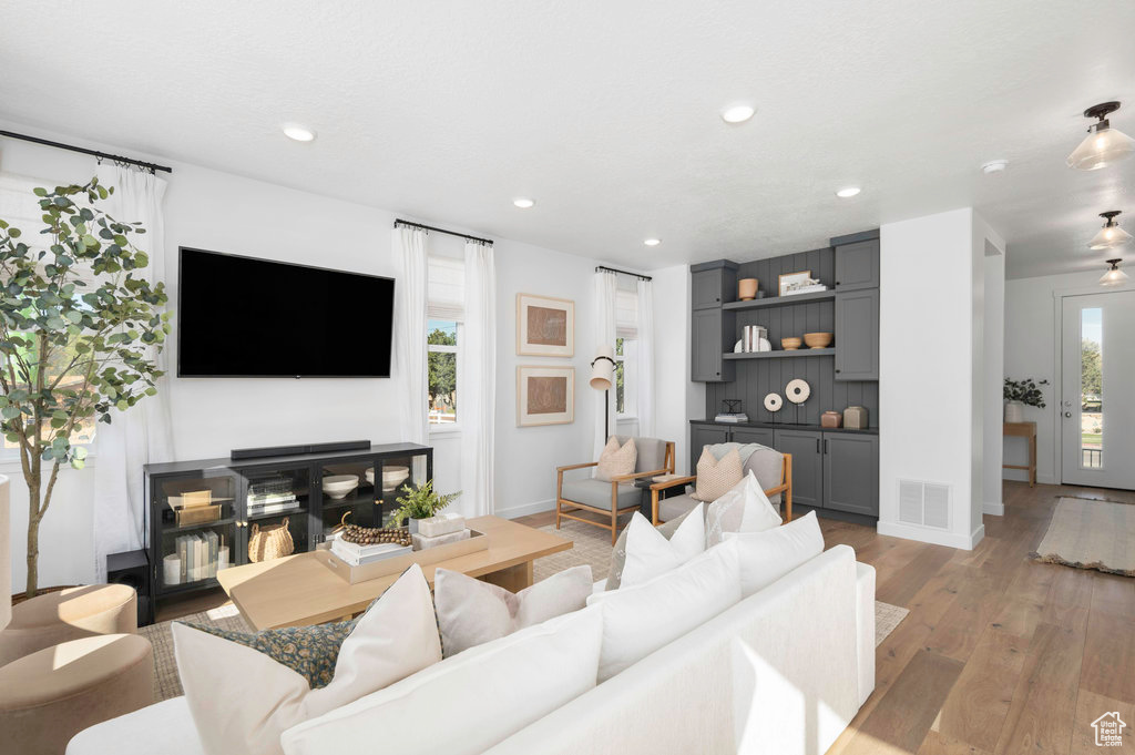 Living area with light wood-style floors, baseboards, recessed lighting, and visible vents