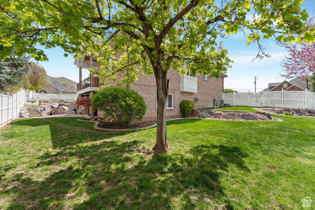View of yard featuring a fenced backyard and a balcony