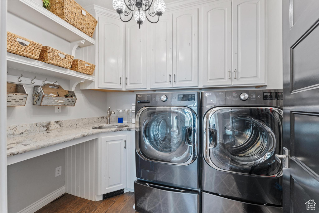 Washroom with independent washer and dryer, cabinet space, a notable chandelier, a sink, and dark wood-type flooring