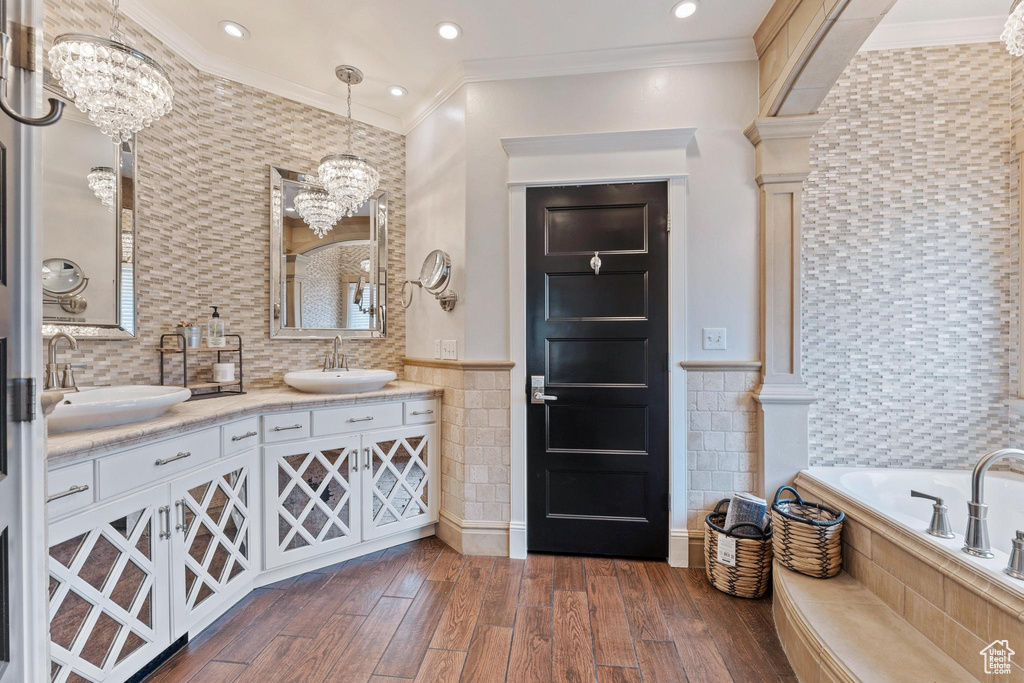 Bathroom featuring a sink, tiled bath, a notable chandelier, and tile walls