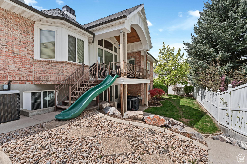 View of playground with a patio area, stairway, central AC, fence, and a yard
