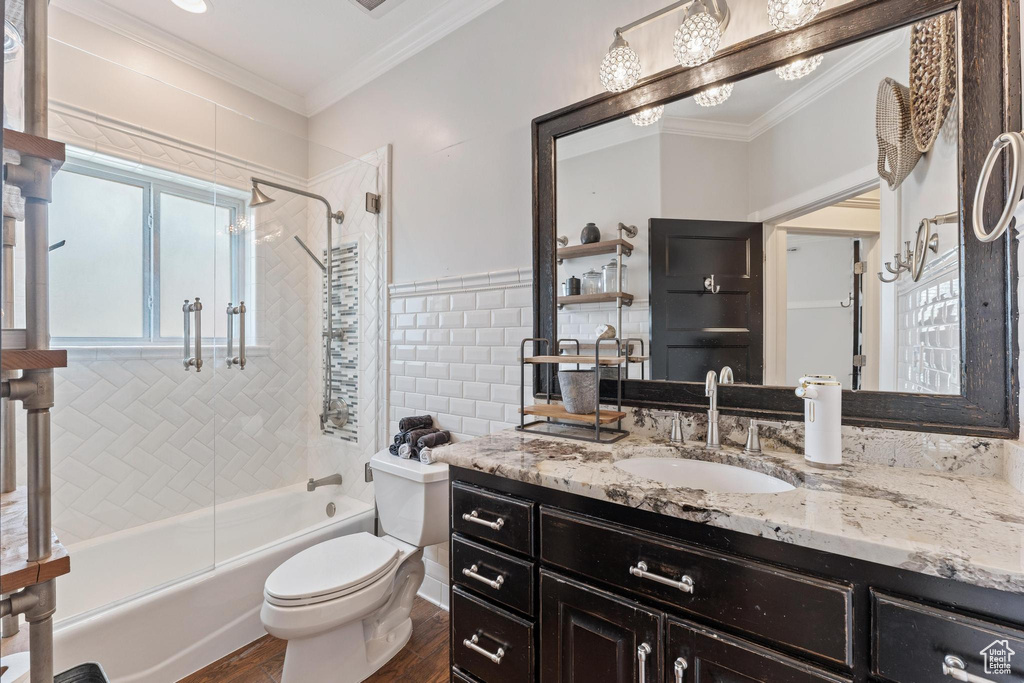 Full bathroom with toilet, ornamental molding, a healthy amount of sunlight, and wood finished floors
