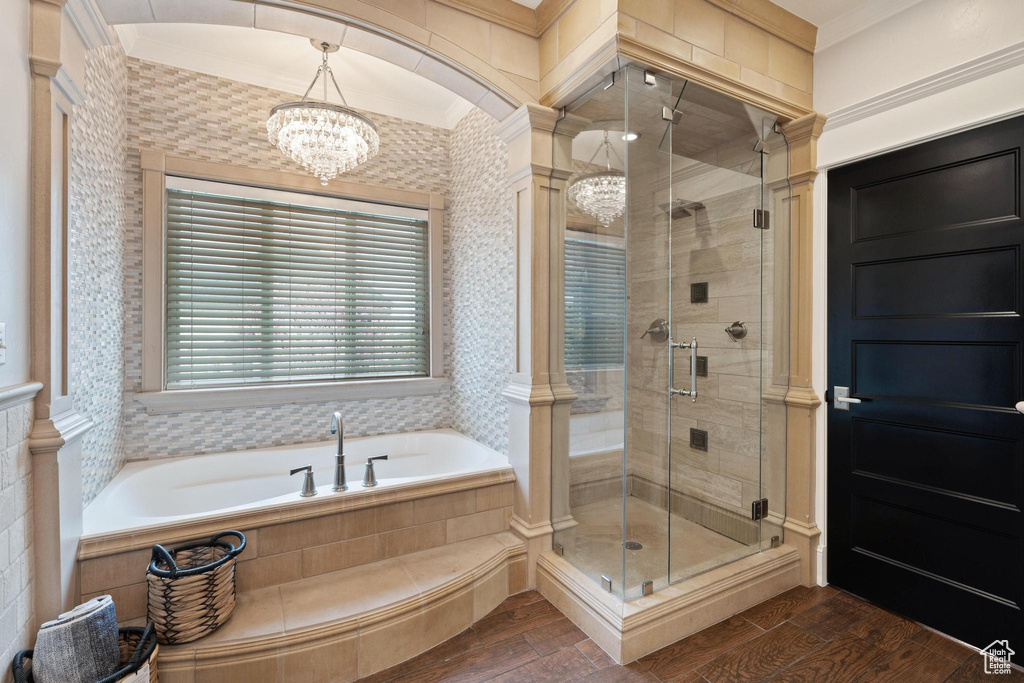 Full bath featuring a notable chandelier, wood finished floors, a bath, and a stall shower