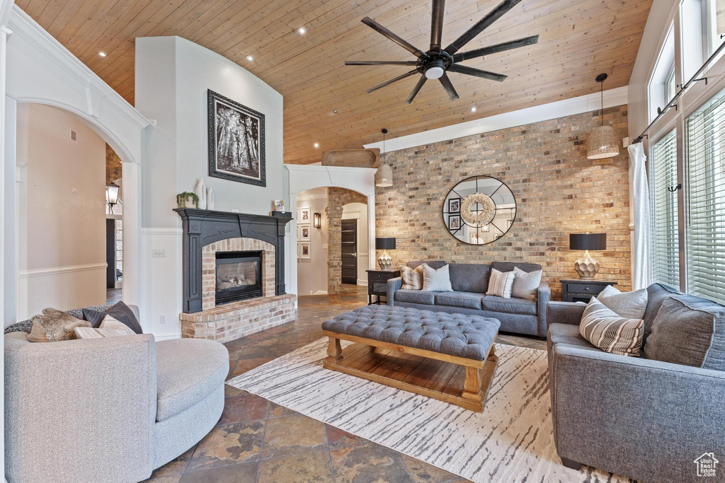Living area with stone tile floors, arched walkways, wooden ceiling, and a towering ceiling