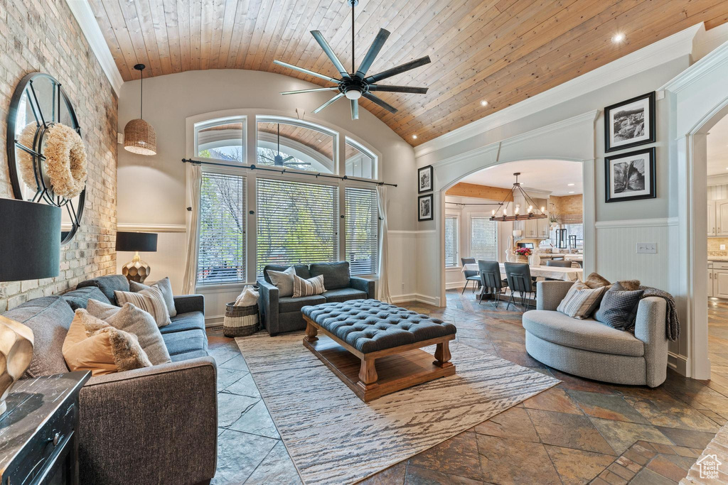 Living room with plenty of natural light, arched walkways, wooden ceiling, ceiling fan with notable chandelier, and lofted ceiling