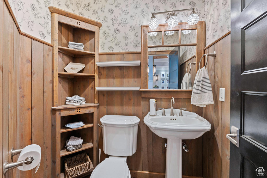 Bathroom with toilet, wallpapered walls, wood walls, and a wainscoted wall