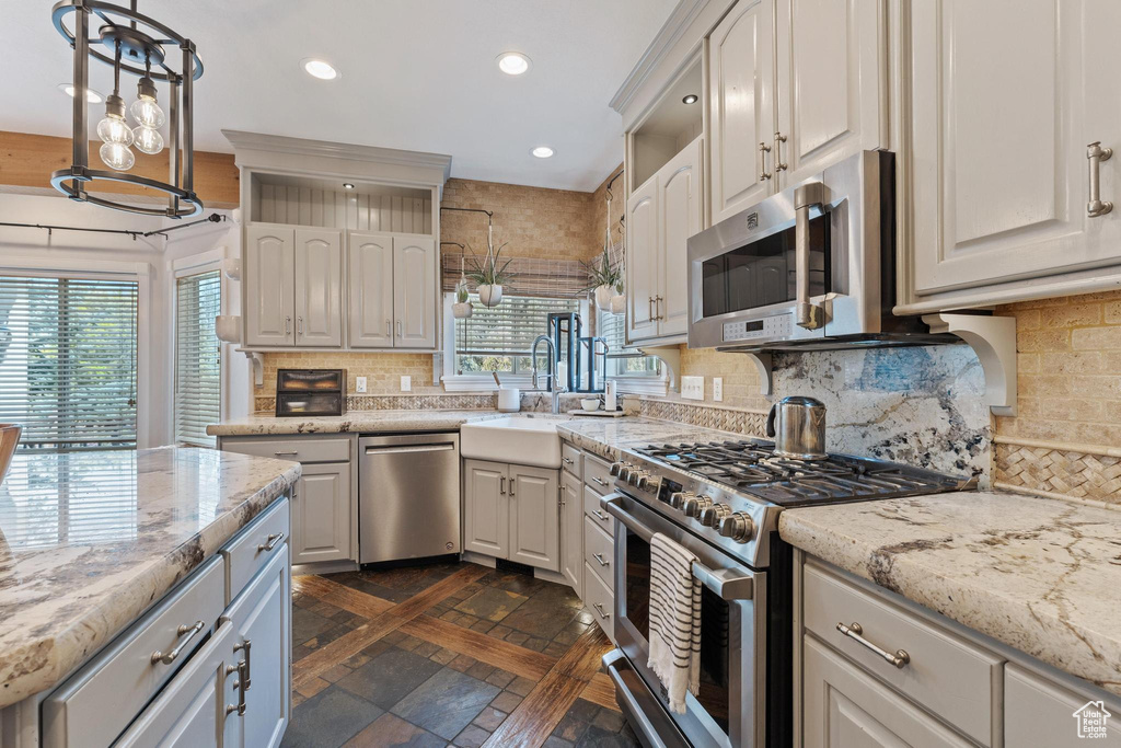 Kitchen with backsplash, decorative light fixtures, appliances with stainless steel finishes, a sink, and recessed lighting