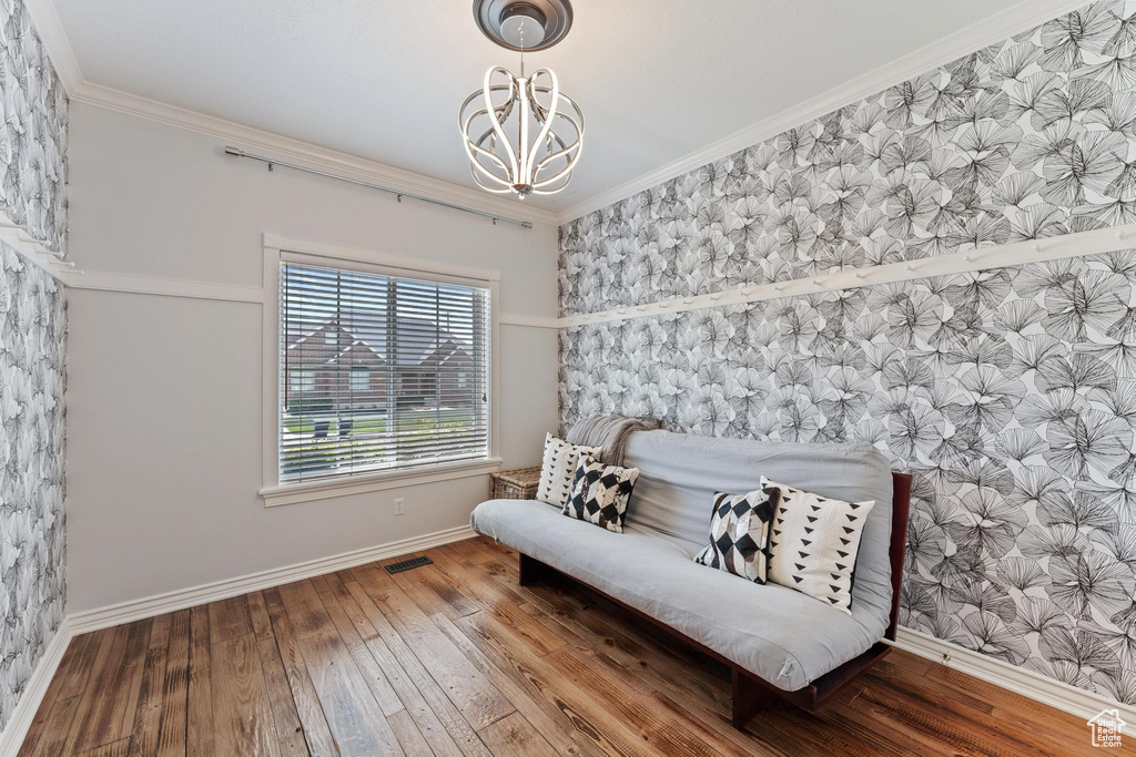 Living area featuring an inviting chandelier, crown molding, visible vents, hardwood / wood-style floors, and baseboards
