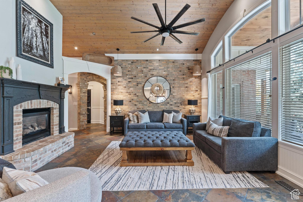 Living room featuring stone tile floors, ceiling fan, wooden ceiling, and high vaulted ceiling