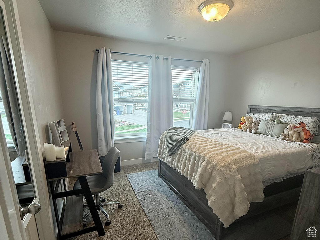 Bedroom featuring visible vents, carpet flooring, and a textured ceiling