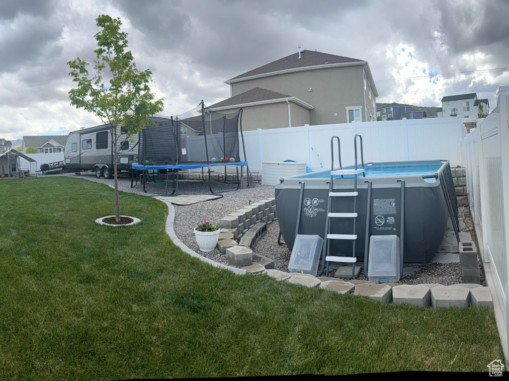 View of yard featuring a patio, a residential view, a fenced backyard, and a trampoline