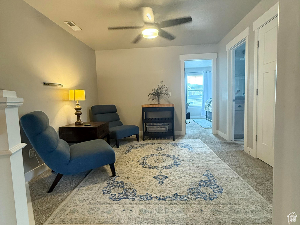 Carpeted living room featuring ceiling fan, a fireplace, a textured ceiling, baseboards, and visible vents