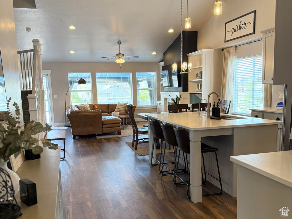 Kitchen featuring a kitchen island with sink, a breakfast bar area, light countertops, recessed lighting, and dark wood-style floors