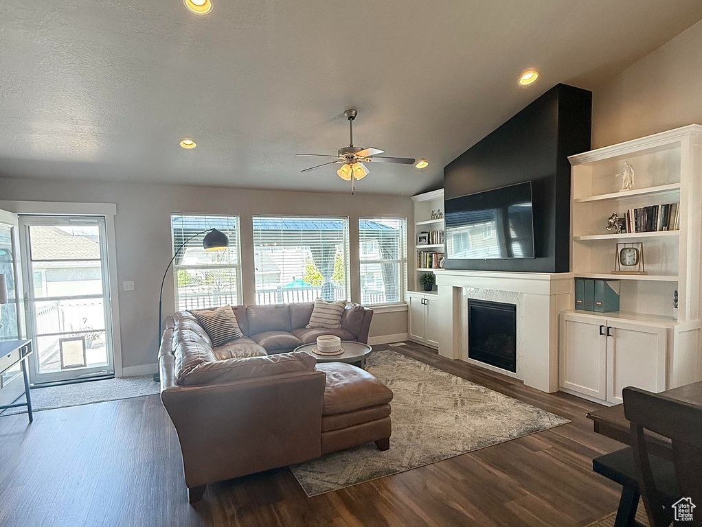 Living area featuring ceiling fan, dark wood finished floors, baseboards, and a fireplace