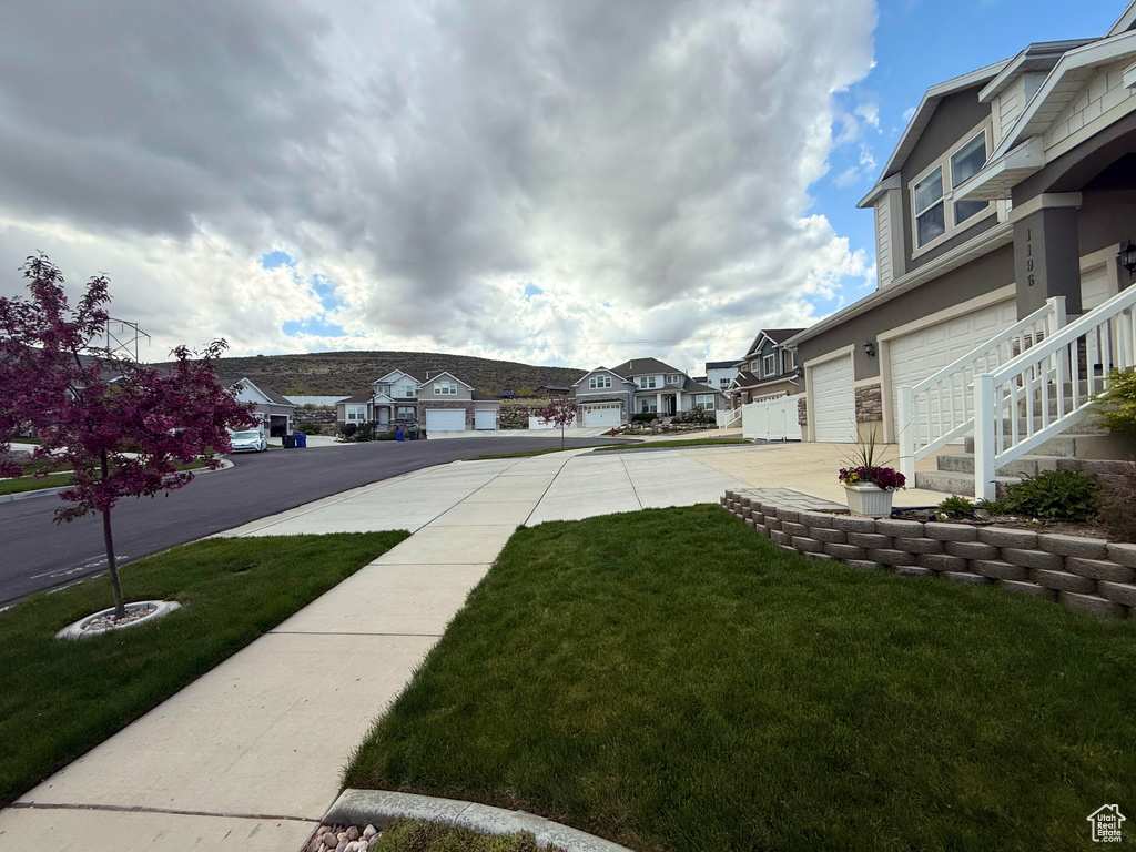 View of yard featuring a residential view, driveway, and a garage